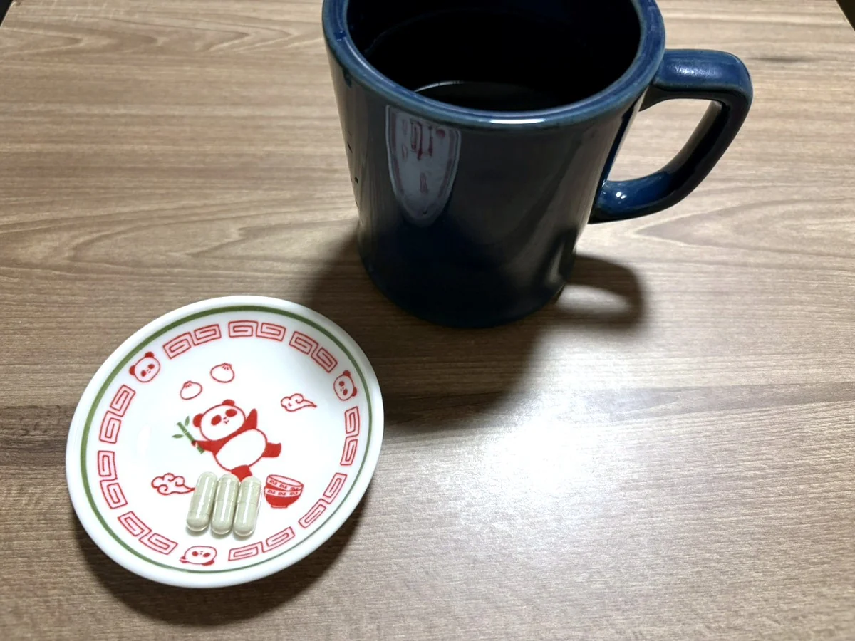 豆皿に入れた1日分のカプセル3粒と、水を入れたマグカップ